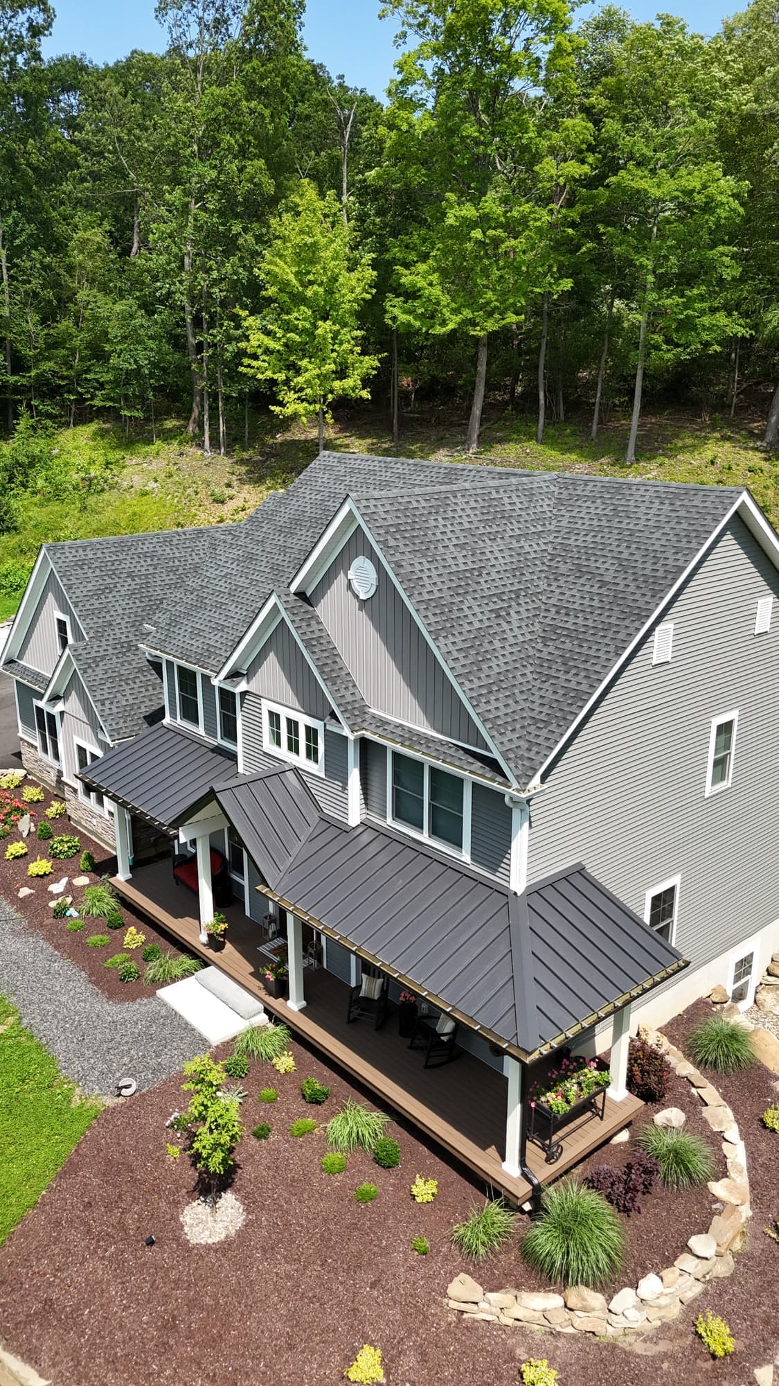 Front of a gray sided home with new windows, metal porch roof and shingle roof in Orange Lake, NY