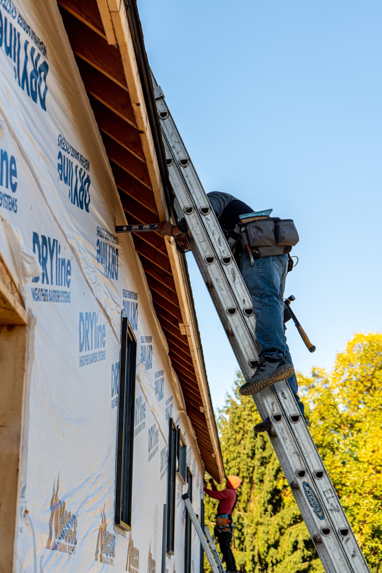 Impact Roofing & Siding installer on a ladder during a siding installation